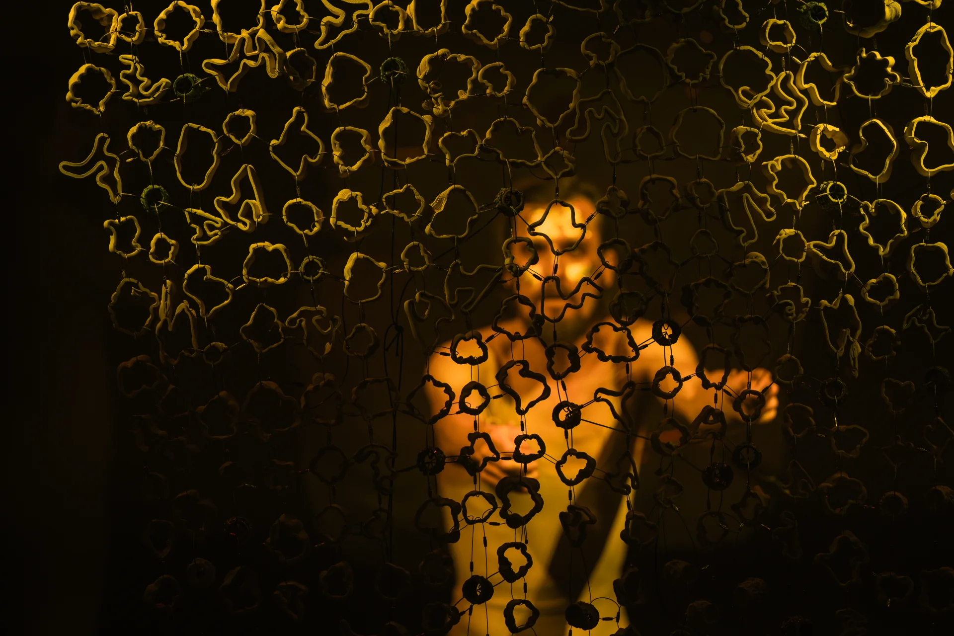 A performer seen through a field of suspended ceramic forms during the Munich world premiere.