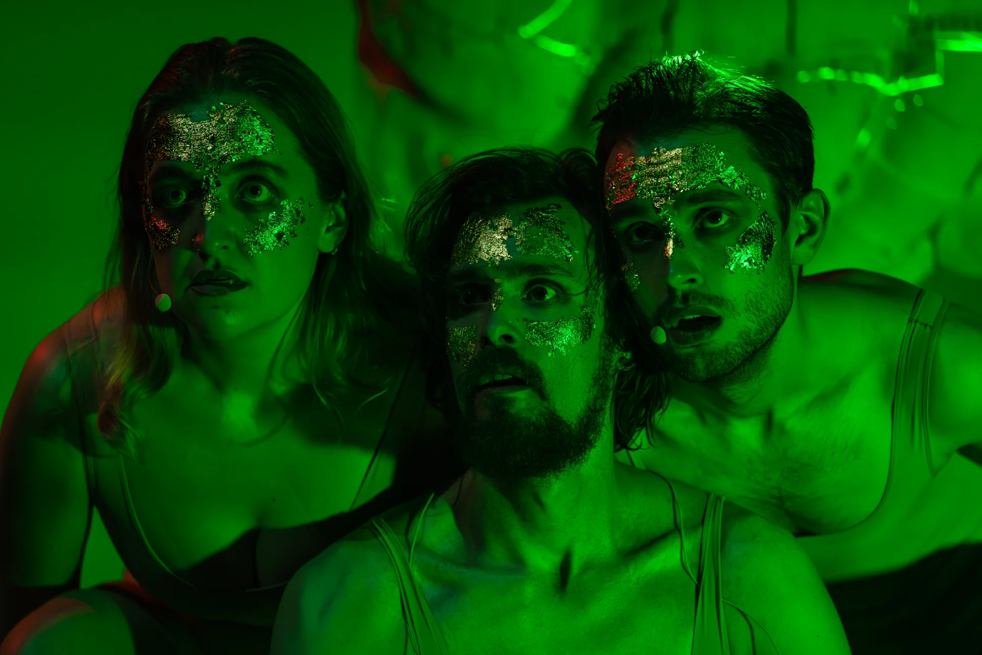 Three performers move through green stage light during the Munich world premiere.