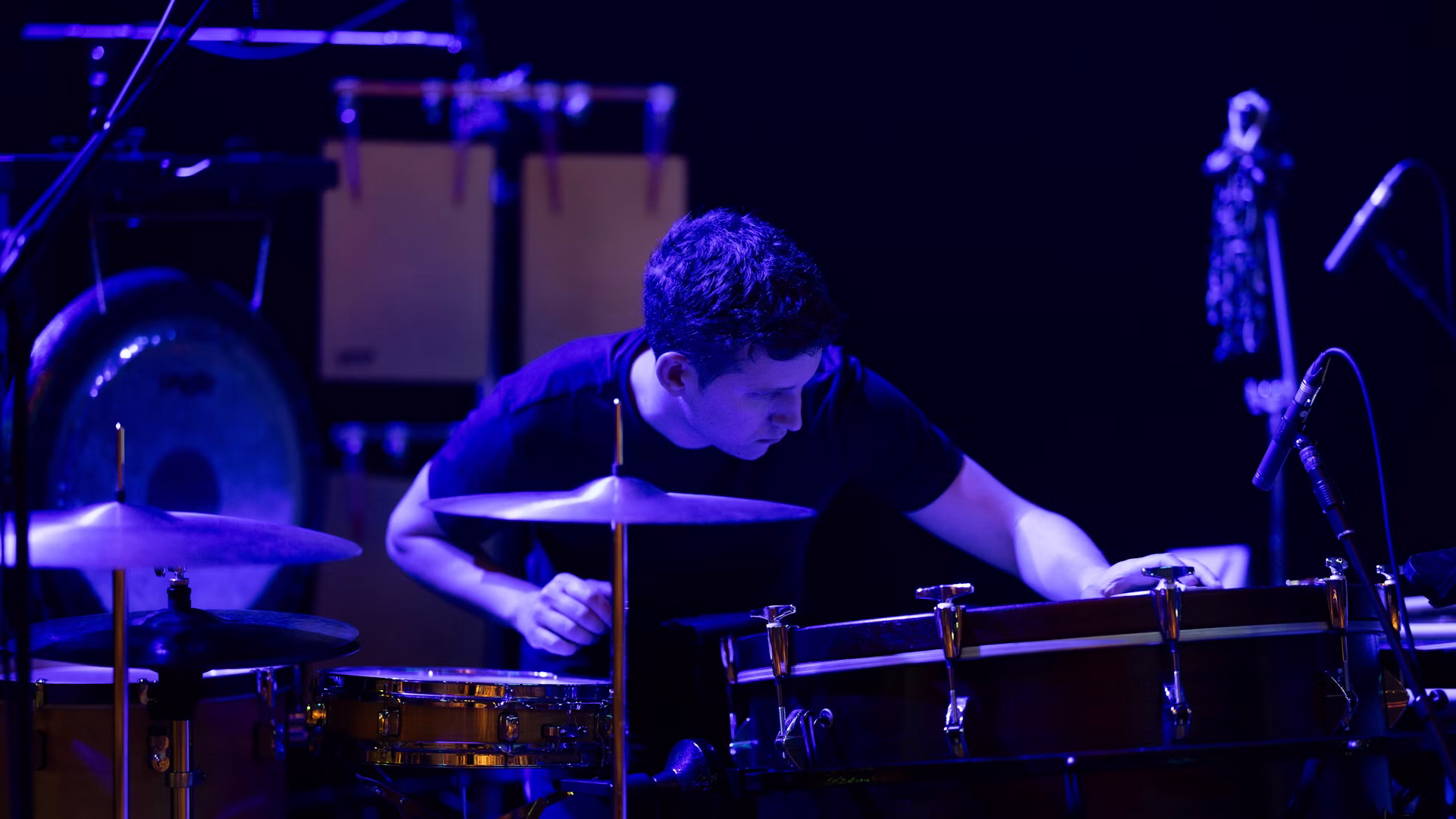 A percussionist performs under blue stage light in Graz.
